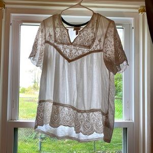 It’s a large white top that’s made from cotton and has a pretty design.